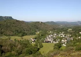 Le village d’Antignac au creux d’une vallée boisée, falaises en arrière-plan