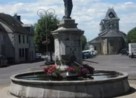 Fontaine fleurie sur la place de Champagnac, l’église en arrière-plan