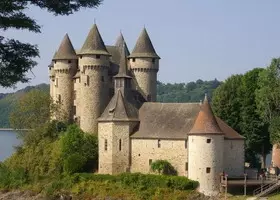 Ch&acirc;teau m&eacute;di&eacute;val aux tours rondes coiff&eacute;es de toits coniques, au bord du lac, &agrave; Lanobre